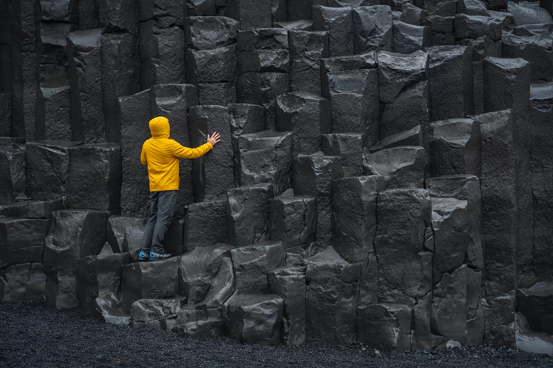 Pessoa com blusa amarela em colunas de basalto