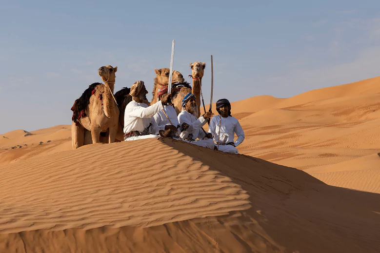 Beduínos com camelos no deserto