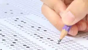 Estudante preenchendo gabarito com lápis roxo