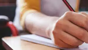 Pessoa em cadeira de rodas escrevendo com lápis